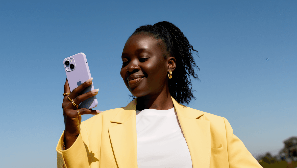 Pessoa sorrindo enquanto conversa pelo celular, usando um blazer amarelo
